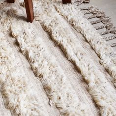 a white rug with wooden legs on the floor