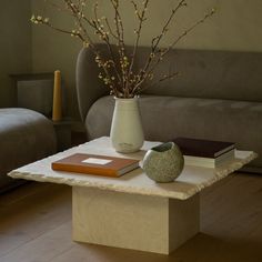 there is a vase with flowers and books on the coffee table in front of the couch