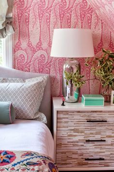 a bedroom with pink wallpaper and white bedding, two lamps on nightstands