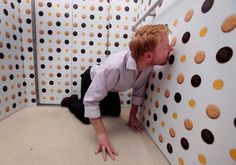 a man leaning against a wall in front of a polka dot wall with cookies on it