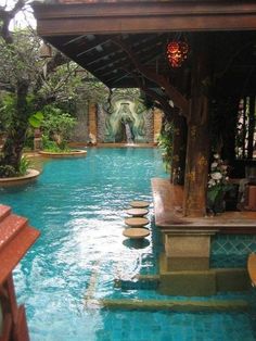 an outdoor swimming pool with benches and trees in the background, surrounded by greenery