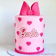 a pink cake with hearts and bows on it's side is decorated with the word barbie