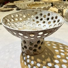 a metal bowl sitting on top of a table covered in white polka dot paper circles