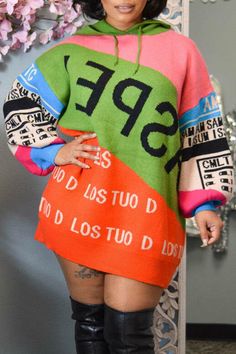 a woman standing in front of a mirror wearing a colorful sweater and thigh high boots