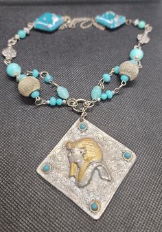 Beautiful and one of a kind, hand made silver and turquoise colored beads featured by a vintage pendant that has a unique image of an Ancient Egyptian King. The beads I used are silver,  stone, crystal and pottery.   The pendant measures 3 inches by 3 inches.   The necklace length is adjustable.  I love this necklace, I hope you will too!  Gift wrapped year round! Handmade Bohemian Beaded Necklace For Collectors, Collectible Bohemian Turquoise Pendant Necklace, Handmade Antique Silver Amulet Necklace, Collectible Bohemian Turquoise Necklace With Large Pendant, Collectible Turquoise Necklace With Natural Stones, Handmade Blue Turquoise Necklace Collectible, Handmade Blue Turquoise Necklace For Collectors, Handmade Blue Turquoise Collectible Necklace, Vintage Blue Necklace With Silver Beads