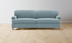 a blue couch sitting on top of a hard wood floor next to a white wall