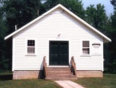 a small white house with steps leading to the front door