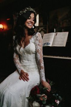 a woman in a white wedding dress sitting next to a piano with an open book behind her