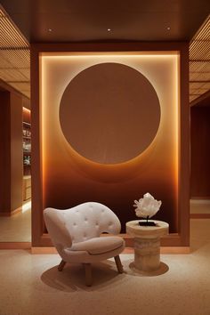 a white chair sitting in front of a wall with a circular painting on it's side