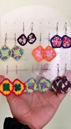 a person is holding up some colorful crocheted earring sets in their hand