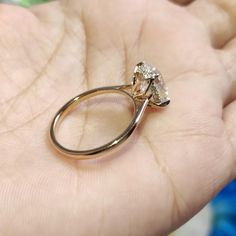 a hand holding a gold ring with a diamond on it's center and two diamonds in the middle