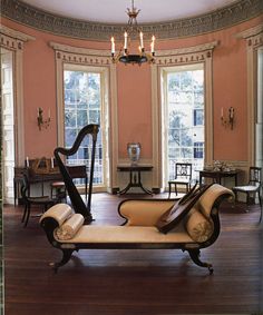 a living room filled with lots of furniture next to two windows and a chandelier