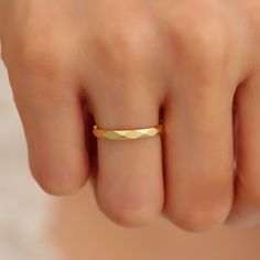 a woman's hand with a gold ring on her finger, showing the band