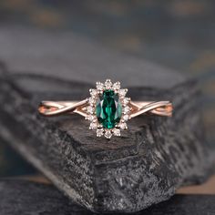 an oval green stone surrounded by white diamonds sits on top of a rock with a diamond halo around it