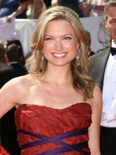 a woman in a strapless red dress smiles for the camera while standing on a red carpet