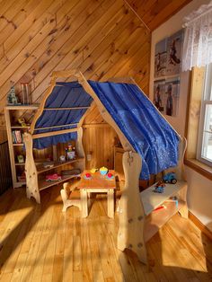 a child's bedroom with wooden walls and flooring, including a blue canopy bed