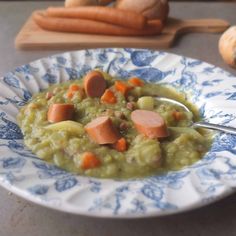 a bowl filled with soup and carrots on top of a table next to bread