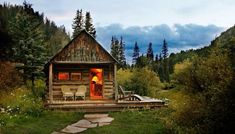 a small cabin in the woods with two chairs