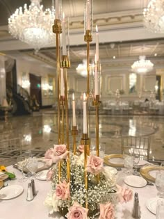 an elegant centerpiece with candles and flowers on a table in a fancy ballroom setting