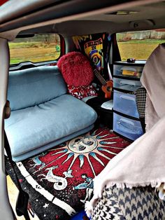 the back seat of a van with various items in it's cargo area, including pillows and blankets