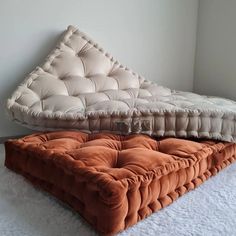 an orange and white futon mattress sitting on top of a white carpeted floor