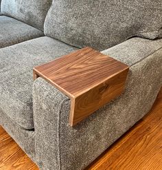 a wooden table sitting on top of a gray couch next to a wooden footstool