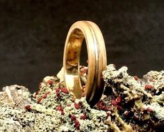 a gold wedding ring sitting on top of a rock covered in lichen and moss