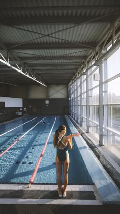 a woman in a bathing suit standing next to a swimming pool