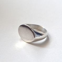 Tabula Rasa. Start your story. A moment of silence before writing, before characters enter, a path is laid. A blank page. The beginning and its freshness. . Kept in the spirit of minimalism and simplicity, a silver signet ring with a streamlined shape and an oval front. The piece is handmade in wax and then cast in sterling silver, hand-finished. . Comfortable. Visible. Ladies'. Men's. Unisex. . The signet ring is polished. Weight of the ring: 10 - 11 g. Size: please choose from the table of ava Sterling Silver Polished Signet Ring, Sterling Silver Signet Ring With Polished Finish, Sterling Silver Rounded Signet Ring With Polished Finish, Modern Oval Sterling Silver Signet Ring, Minimalist Oval Sterling Silver Signet Ring, Minimalist Silver Signet Ring With Polished Finish, Minimalist Sterling Silver Dome Ring, Oval Sterling Silver Dome Ring For Everyday Wear, Minimalist White Gold Signet Ring