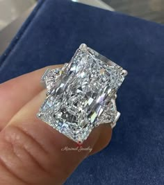 a diamond ring is being held up in front of a blue velvet box with an inscription on it