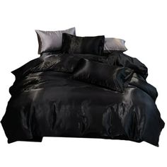 a bed with black sheets and pillows on top of it, in front of a white background