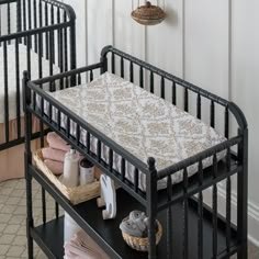 a baby crib in the corner of a room next to a shelf with items on it