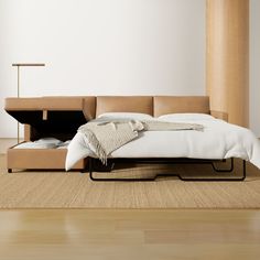 a bed sitting on top of a wooden floor next to a white pillow and blanket