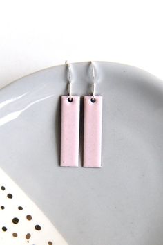 Soft pastel pink earrings handmade by firing enamel onto copper in a kiln at a temperature of over 800 degrees. The geometric rectangular earrings measure approximately 30mm x 8mm and would make a fab gift for any lover of stylish jewellery accessories. These earrings are backed with counter enamel to insure comfort and strength. They come complete with 925 Sterling silver earring wires and would look fabulous with any outfit all year round. CUSTOMISE: Please contact me if you would like a bespo Handmade Square Pink Jewelry, Handmade Pink Square Jewelry, Modern Pink Rectangular Earrings, Rectangular Pink Earrings For Gifts, Pink Rectangular Earrings As Gift, Pink Rectangular Earrings For Gift, Pink Rectangular Earrings For Gifts, Handmade Minimalist Pink Earrings, Pink Square Jewelry Gift