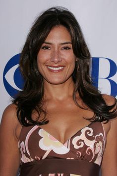 a woman in a brown and pink dress smiling at the camera with her eyes closed