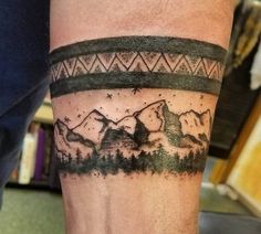 a man with a tattoo on his leg has a mountain scene and stars in the sky