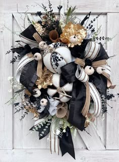 the wreath is decorated with black and white pumpkins, gold leaves, and feathers