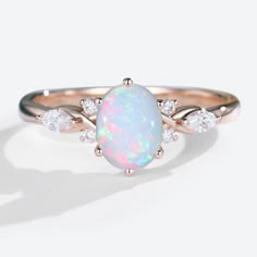 a white opal and diamond ring with rose gold accents on the band, set against a plain background