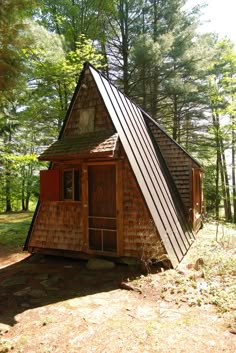 a small cabin in the woods with a roof made out of wood and metal strips