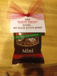 a bag of mini pretzels sitting on top of a wooden table next to a person's foot