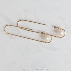 The Zosia earrings are a modern take on the classic pearl earring. Handmade from 18 gauge gold filled wire, these are suitable for sensitive skin and perfect for everyday wear. Understated enough for the office but enough of a statement to show up during those Zoom meetings. • 14k gold filled wire • Freshwater pearls • Measures approx. 2" long Minimalist Metal Pearl Drop Earrings, Elegant Brass Wrap Earrings With Ear Wire, Minimalist Wire Wrapped Pearl Drop Earrings, Handmade Minimalist Pearl Earrings For Everyday, Minimalist Handmade Pearl Earrings For Everyday, Minimalist 14k Gold Filled Earrings With Pearl Charm, Minimalist Pearl Drop Threader Earrings, Minimalist Gold Pearl Earrings 14k Gold Filled, Minimalist Gold Pearl Earrings In 14k Gold Filled