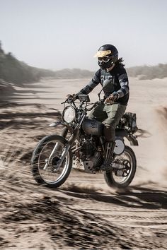 a man riding on the back of a motorcycle down a dirt road