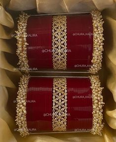 two red boxes with gold trims and pearls on the sides are sitting in a box