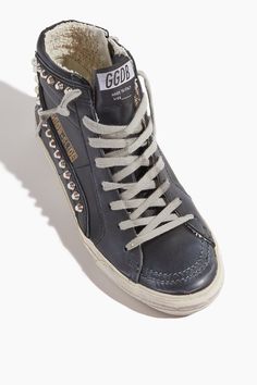 The Golden Goose Slide Sneaker in Black has an edgy look you'll love. These high rise sneakers have stud detailing with a black leather upper and their signature star. Fits true to size, take your normal size High top sneakers Side zipper Stud detailing Leather upper Classic Black High-top Sneakers With Textured Sole, Black Leather High-top Sneakers, Casual Black High-top Sneakers With Perforations, Golden Goose High Tops, Designer Black High-top Sneakers With Studded Outsoles, Star Fits, Black Leather High-top Sneakers With Textured Sole, Carhartt Shop, Golden Goose Slide