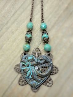 Experience the timeless beauty of our Antiqued Brass Filigree Heart Assemblage Necklace. With vintage romantic Victorian filigree and a stunning patina heart, this necklace is perfect for any occasion. The Czech glass beaded chain adds an extra touch of elegance, making it the perfect gift for someone special. Antiqued brass filigree Antiqued brass heart with patina and rhinestone Faceted Czech glass beads Antiqued brass chain Lobster clasp closure Chain measures 18" Pendant is 3" One of a Kind Heart-shaped Bohemian Wedding Jewelry, Bohemian Heart-shaped Wedding Jewelry, Vintage Filigree Heart Pendant Jewelry, Victorian Heart Necklace With Heart Charm, Elegant Patina Pendant Necklace, Elegant Pendant Necklace With Patina, Vintage Heart Filigree Jewelry, Vintage Heart-shaped Filigree Jewelry, Vintage Heart Shaped Jewelry With Intricate Design