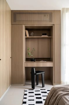 a bedroom with a bed, desk and chair next to a wooden shelf on the wall