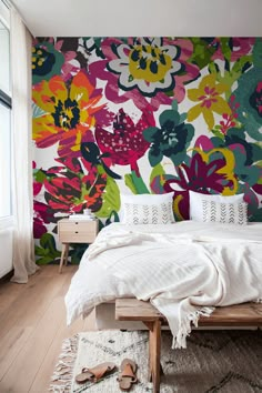 a bedroom with colorful floral wallpaper and white bedding, wooden flooring and two nightstands