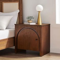 a bed with white pillows and a wooden night stand