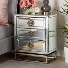 a mirrored cabinet with two drawers and flowers on the side table next to a couch