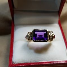 Lovely And Unusual 14kt Yellow Gold Amethyst Ring. High Quality Amethyst Bezel Set Sideways In Between Two Rows Of Channel Set Round Diamonds With A Cabochon Ruby On Either Side. In Excellent Condition, Is About A Size 7 Now, But Sizable. All Stones Are Genuine And 4 Grams In Weight. Elegant Multi-stone Amethyst Ring In Yellow Gold, Elegant Multi-stone Amethyst Ring Gift, Luxury 14k Gold Purple Rings, Luxury Purple 14k Gold Rings, Luxury Amethyst Ring Emerald Cut, Luxury Multi-stone Amethyst Jewelry, Luxury 14k Gold Purple Jewelry, Luxury Amethyst Multi-stone Jewelry, Luxury Emerald Cut Amethyst Ring